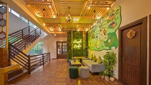 Un vestíbulo espacioso con suelo de madera en patrón de espiga, una escalera con barandilla de madera, una pared verde con un letrero de neón y un mural de mapa.