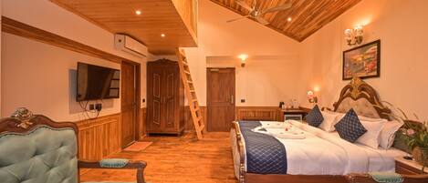 A bedroom with a wooden ceiling, a bed with a quilted cover, a television on the wall, and a wooden wardrobe.