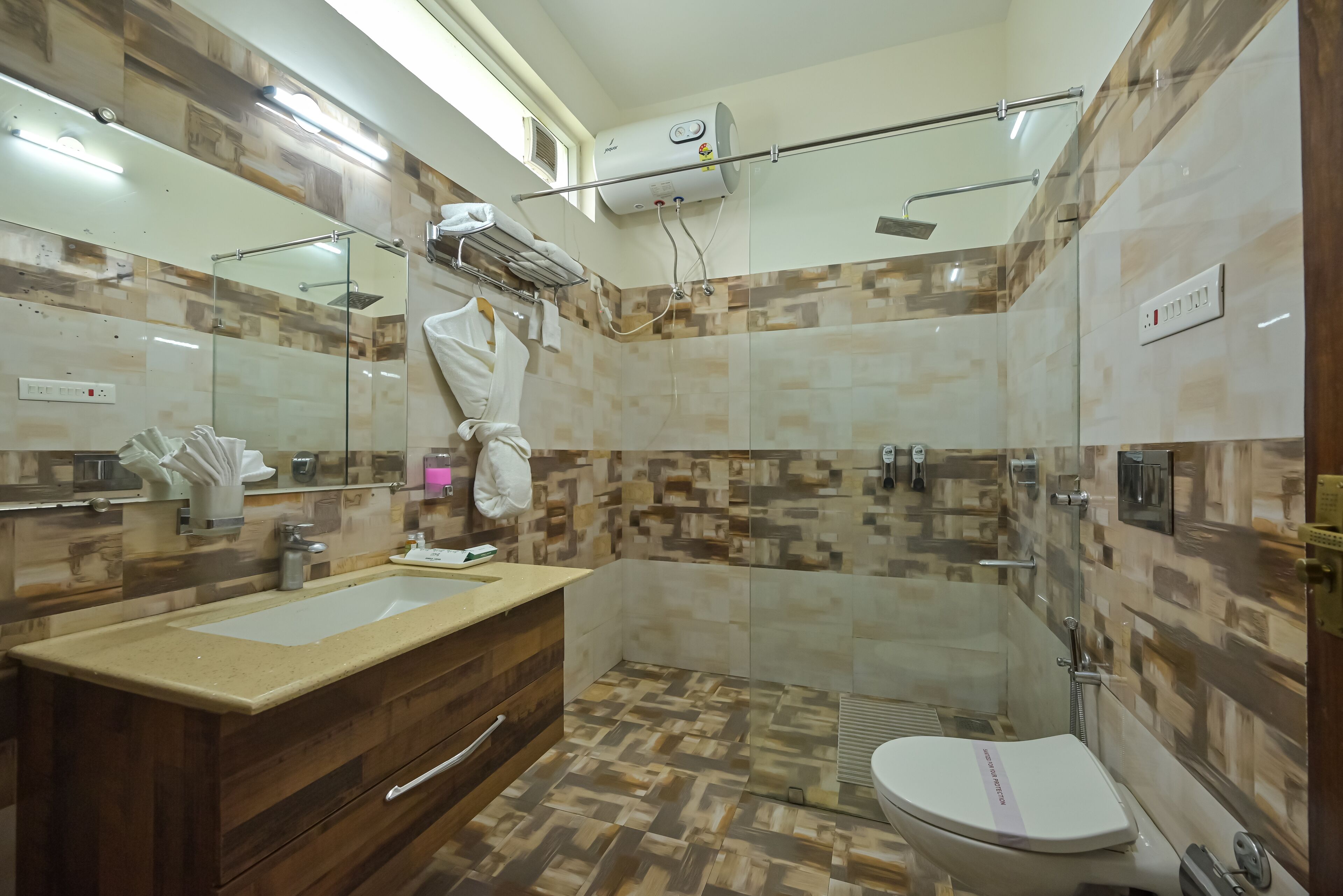 A bathroom with a wooden vanity, a large mirror, a shower with a glass enclosure, and a toilet.