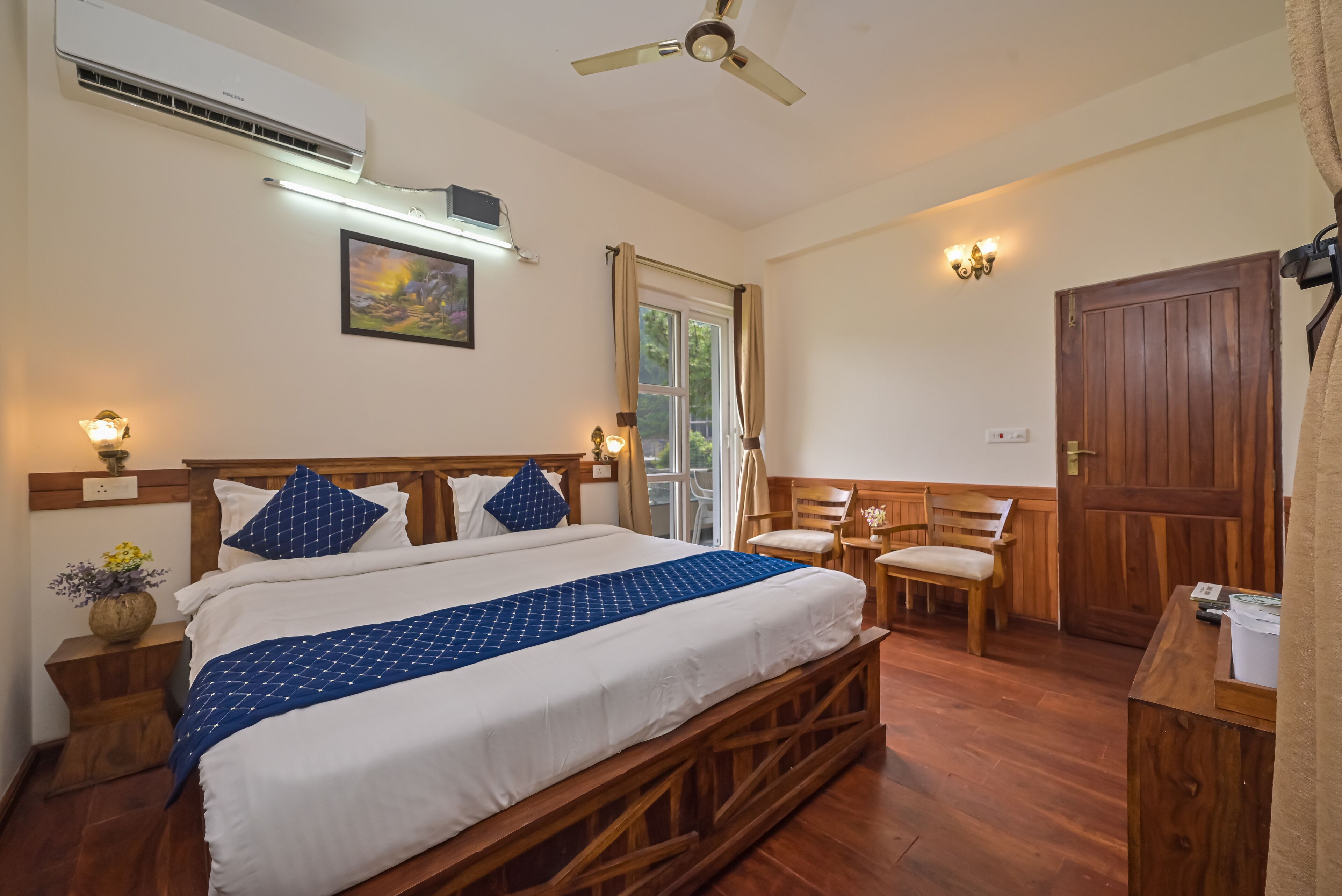 A well-lit bedroom with a wooden bed, a ceiling fan, and a wooden desk with a chair.