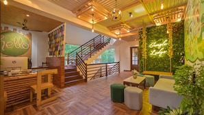 Un interior moderno con un mostrador de recepción de madera, una escalera y una pared verde con el letrero 'Tungle Lodge'.