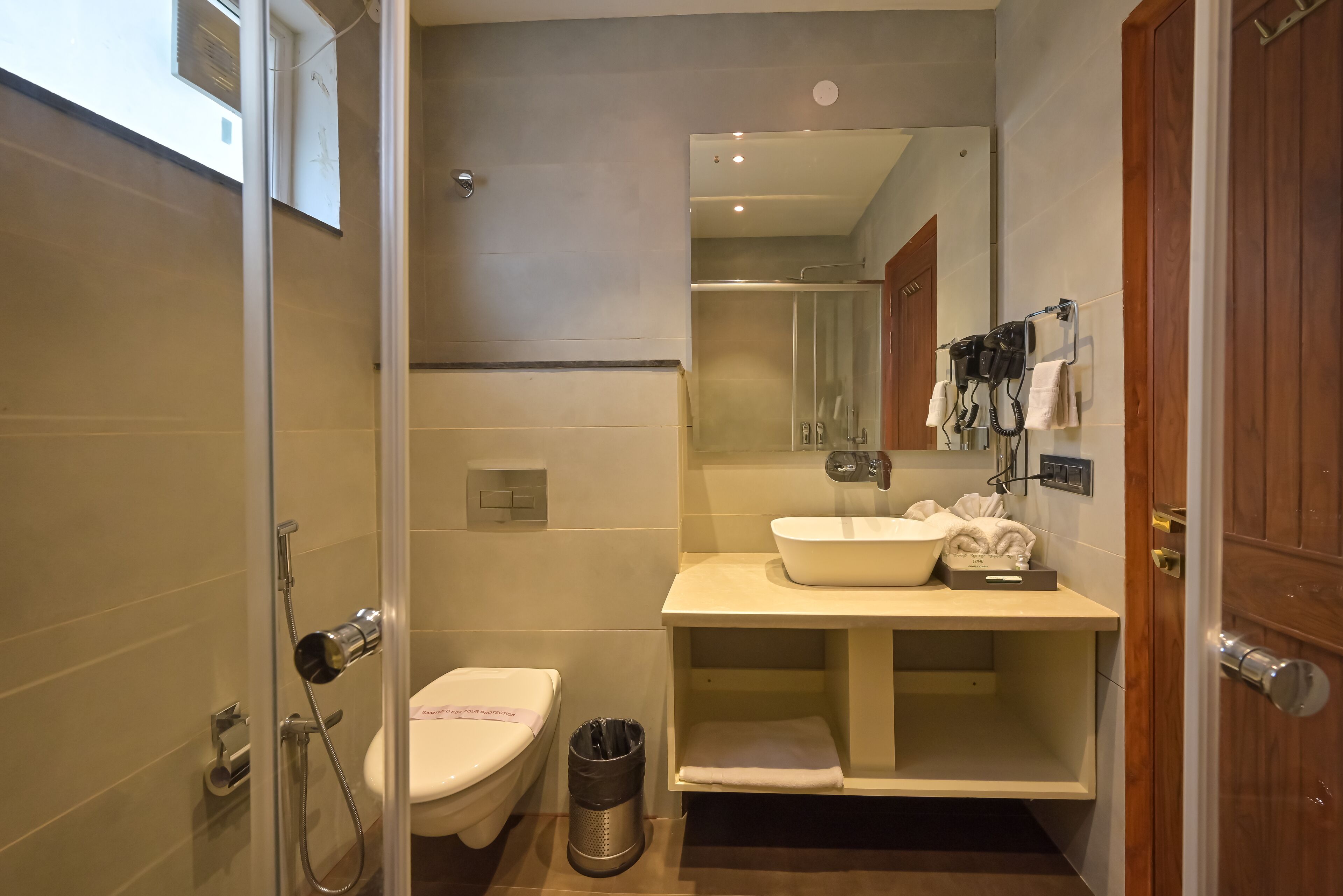 A modern bathroom with a glass-enclosed shower, a white toilet, a sink with a mirror, and a towel rack.