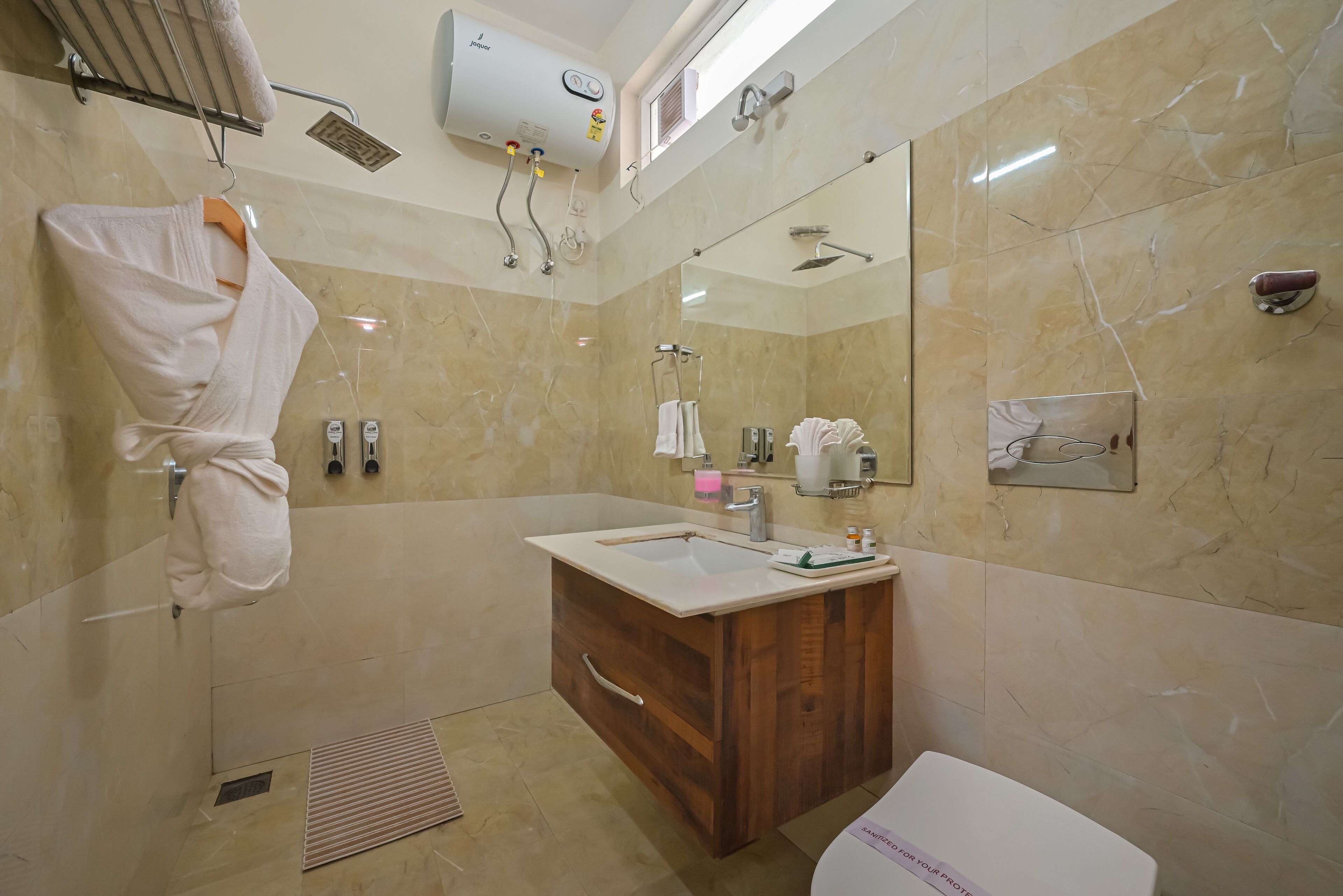 A modern bathroom with a marble wall, a wooden vanity, a large mirror, and a towel hanging on the wall.