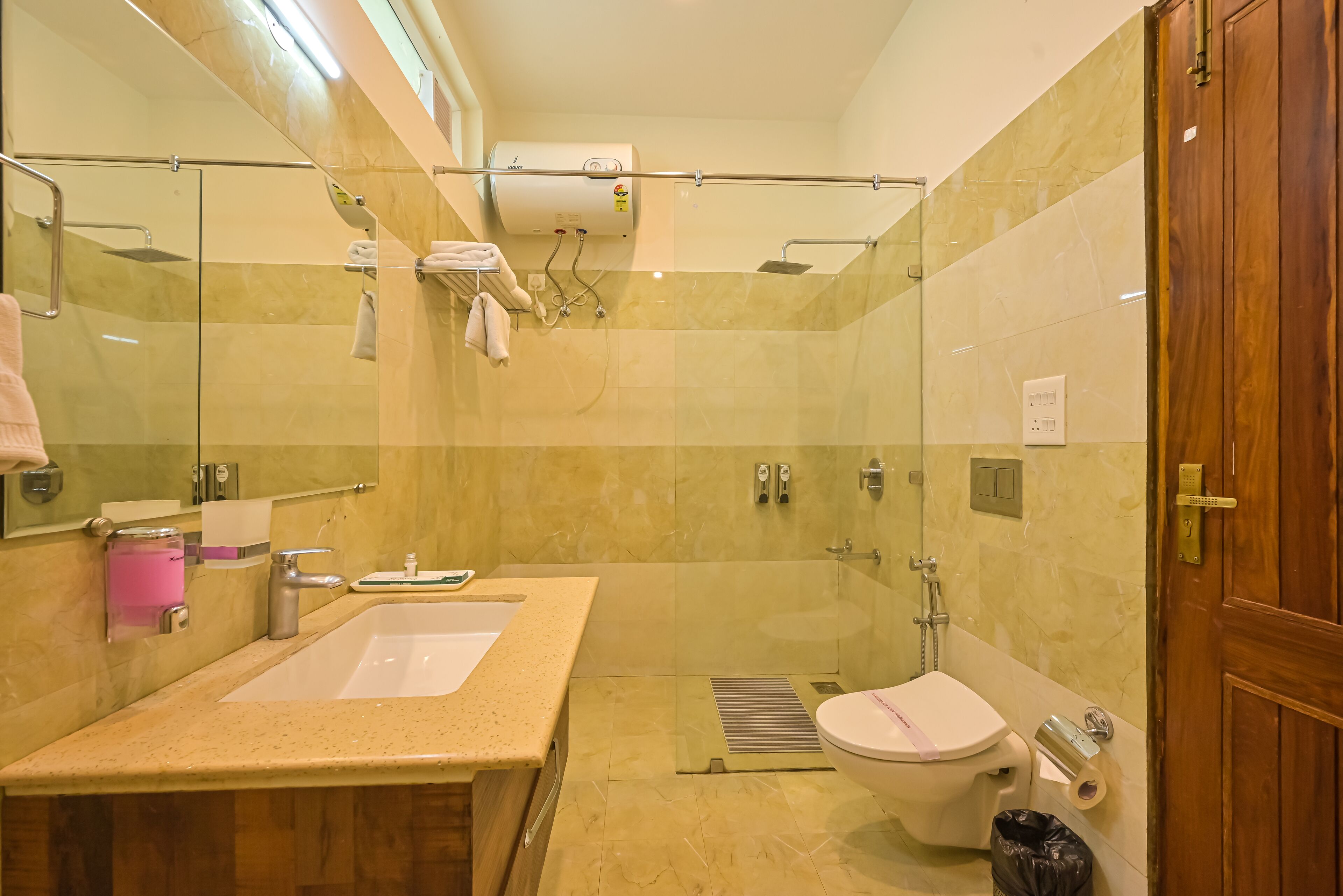 Un baño moderno con ducha envuelta en vidrio, lavabo con encimera de mármol y retrete.