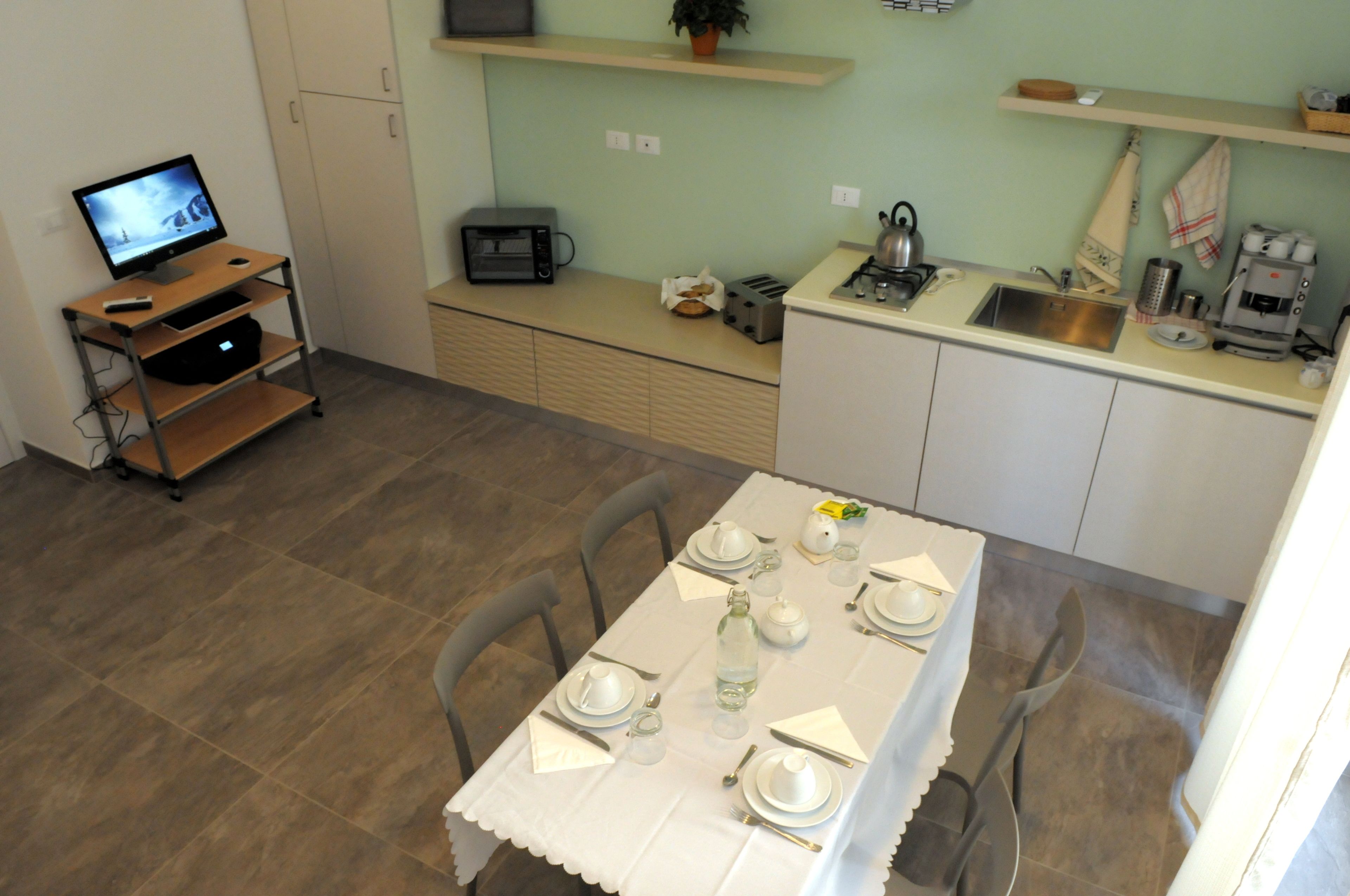 A compact kitchen with a dining area, a small refrigerator, a microwave, and a coffee maker.