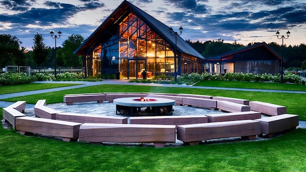 A modern building with large glass windows, a fire pit, and outdoor seating. - Palac Mala Wies (Belsk Duzy)
