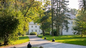 A pathway leading to a white building surrounded by lush greenery and trees. - Palac Mala Wies (Belsk Duzy)