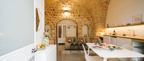 Una cocina moderna con pared de piedra, muebles blancos y una araña.