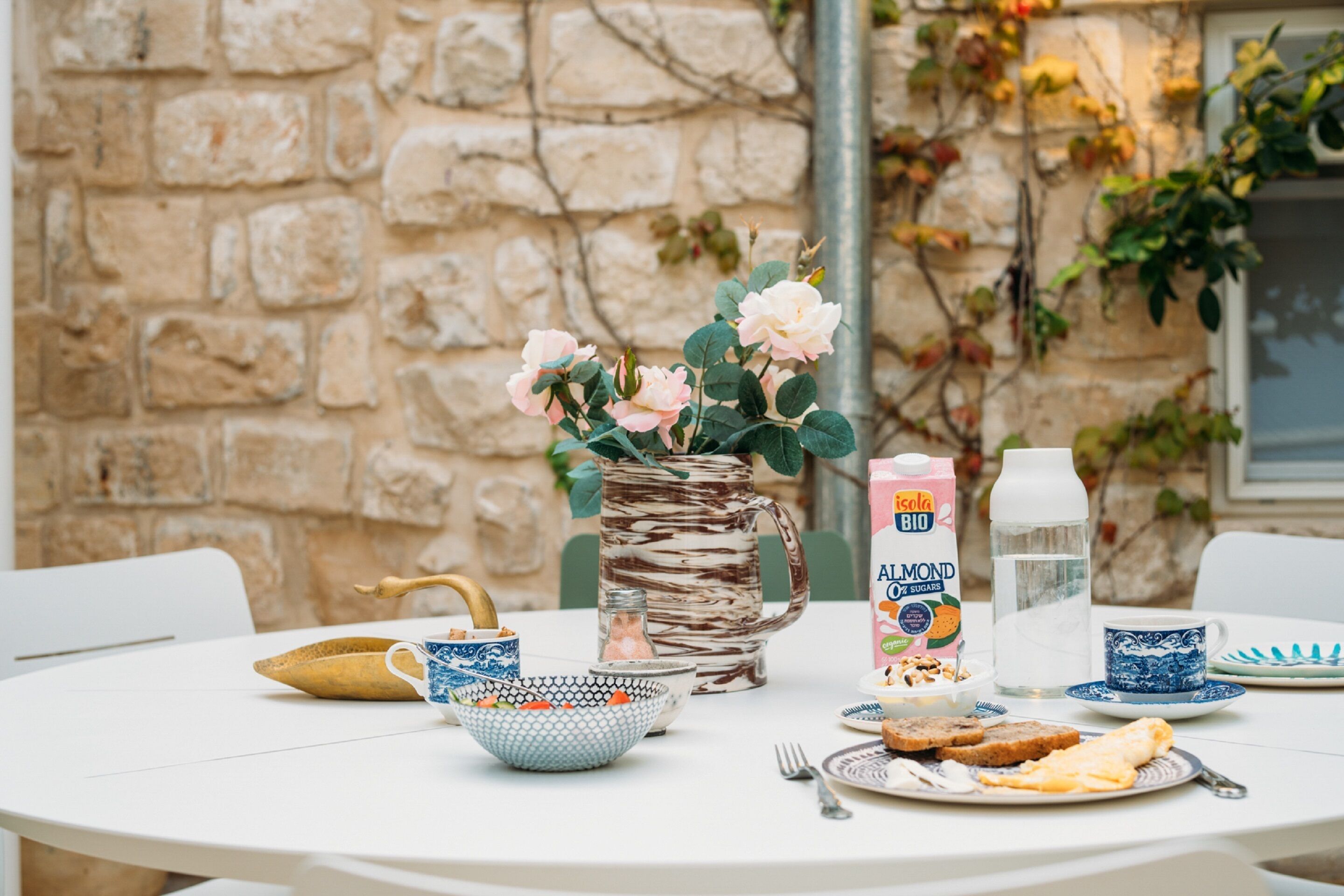 A round table with a pitcher, a bowl, a jug, and plates with food.