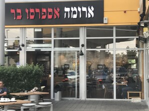 A restaurant with a glass facade and outdoor seating.