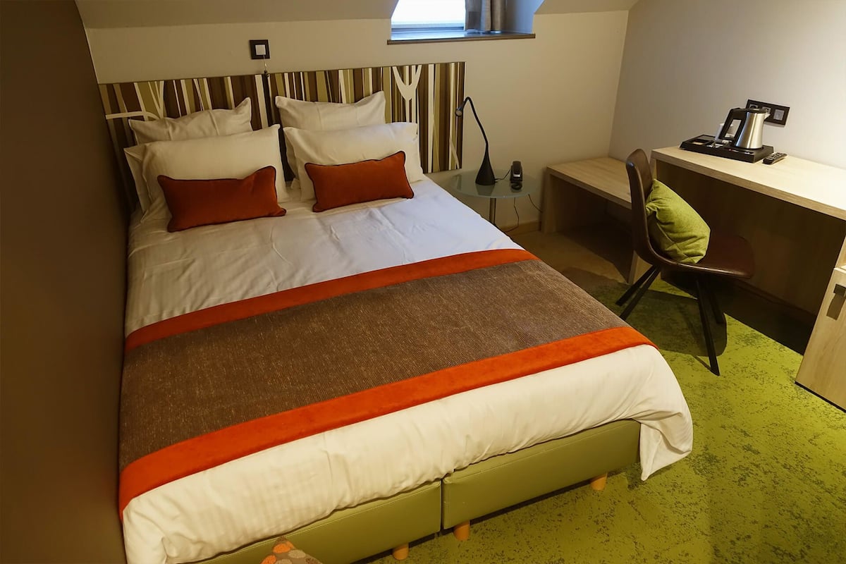 A hotel room with a bed, a desk, and a chair.