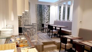 A modern dining area with a buffet setup, seating arrangements, and a view through a patterned wall. - Hôtel du Parc (Ath)