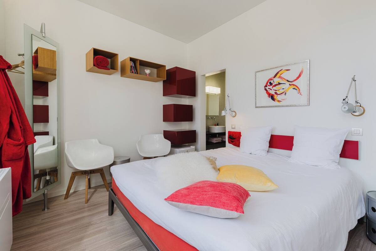 Ein modernes Schlafzimmer mit Bett, Sessel, Schreibtisch und Spiegel.