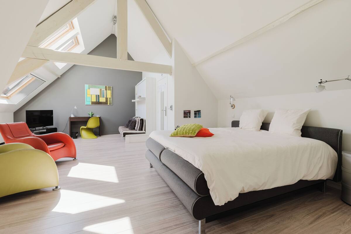Ein modernes Schlafzimmer mit einem großen Bett, einem Dachfenster und Blick auf die Stadt.