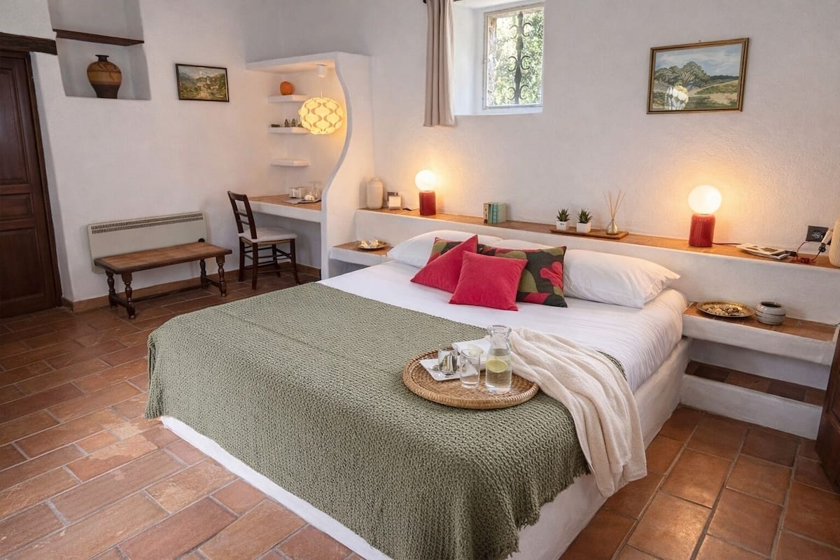 A bedroom with a bed, bedside tables, a bench, a window, and a door.
