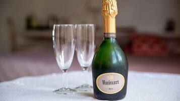 A Ruinart champagne bottle on a white tablecloth with two empty glasses.