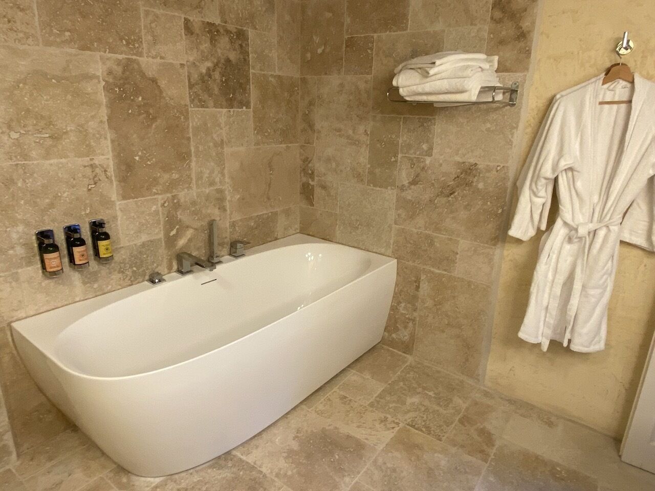 Une salle de bain moderne avec une baignoire sur pieds, un porte-serviettes et un peignoir accroché au mur.
