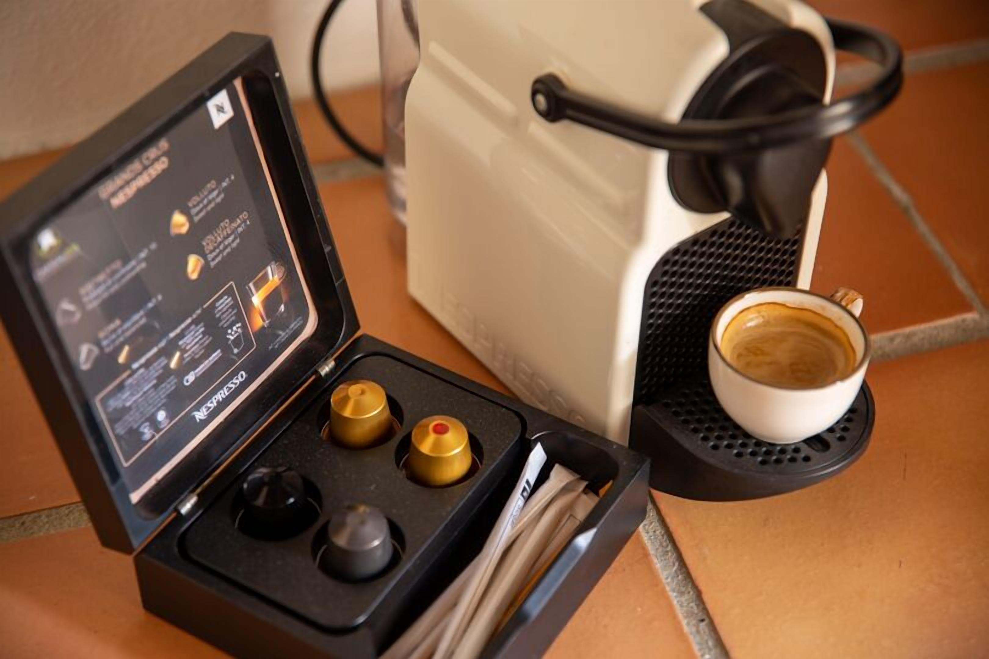 Una máquina de café Nespresso con una taza de café sobre una bandeja negra.