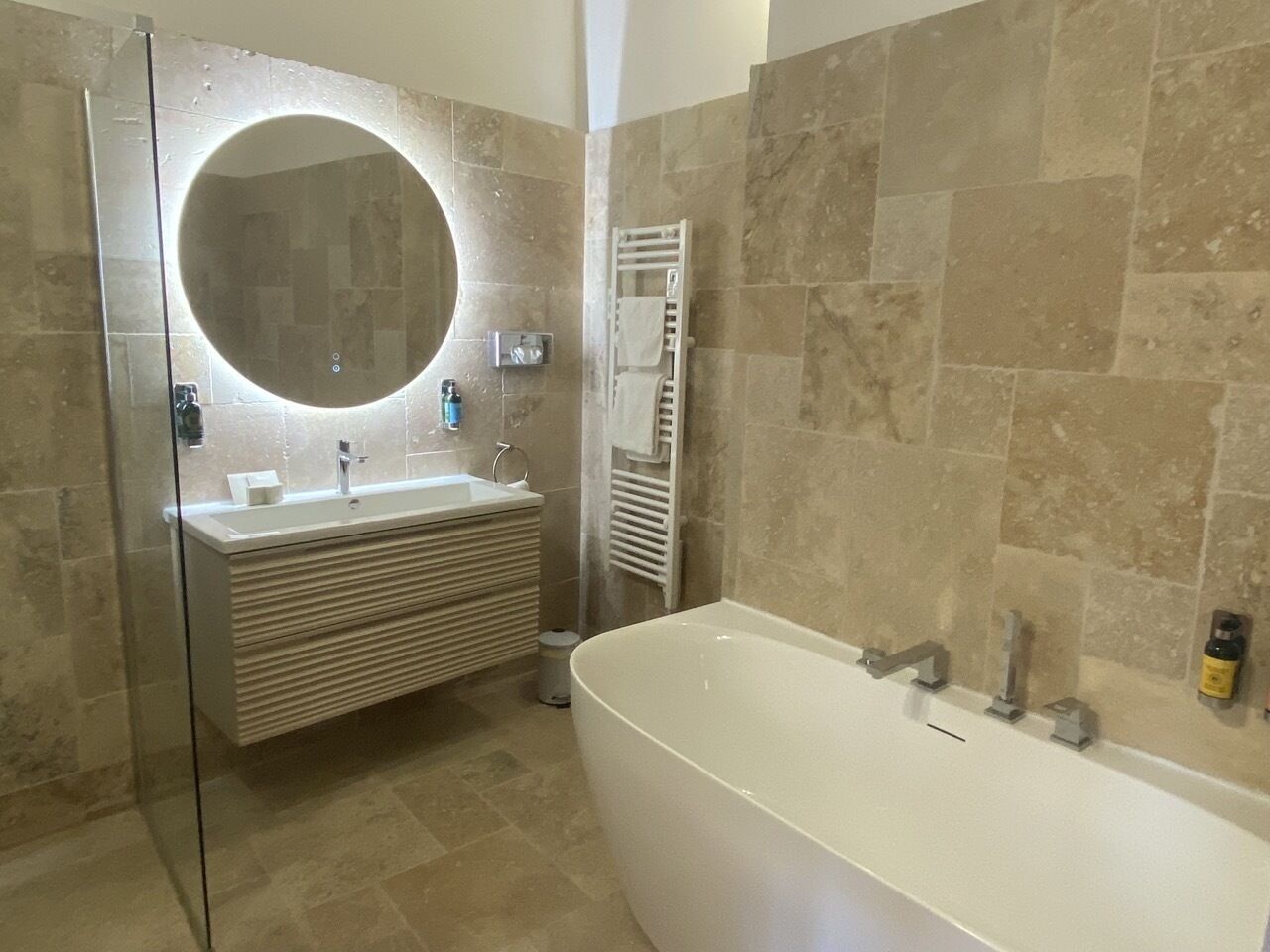 A modern bathroom with a freestanding bathtub, a glass-enclosed shower, and a vanity with a mirror.