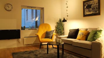 A living room with a yellow armchair, a grey sofa, a black coffee table, and a window with blinds.