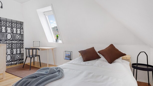 Un dormitorio con cama, escritorio, silla, mesita y ventana.