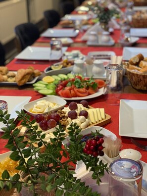 A long table with various food items and a centerpiece of greenery. - Otel Familia (Orhangazi)
