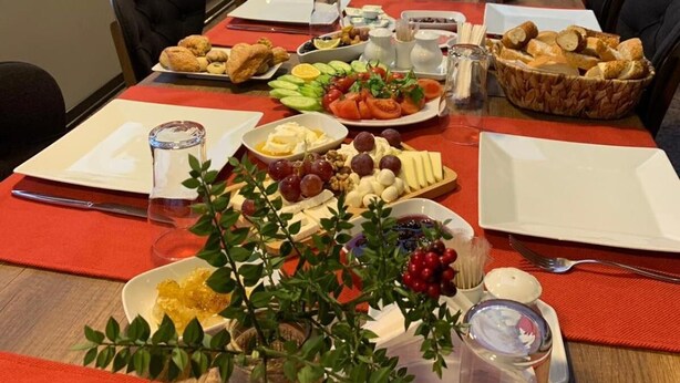 A long table set for a meal with various food items and a view of the city through large windows. - Otel Familia (Orhangazi)