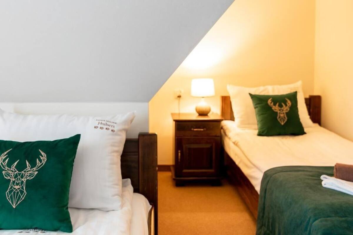 Et hotelværelse med to senge, et natbord med en lampe, og en pude med et hjortedesign.