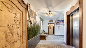 A hallway with a wooden wall carving, a patterned carpet, a wooden bench, and a door with an elevator. - Dworek Mysliwski Hubert (Bukowina Tatrzanska)
