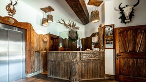 A rustic reception desk with a wooden finish, a stainless steel refrigerator, and a wooden door. - Dworek Mysliwski Hubert (Bukowina Tatrzanska)