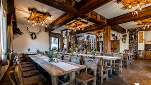 A rustic dining area with wooden tables and benches, a chandelier, and antler decorations on the walls. - Dworek Mysliwski Hubert (Bukowina Tatrzanska)