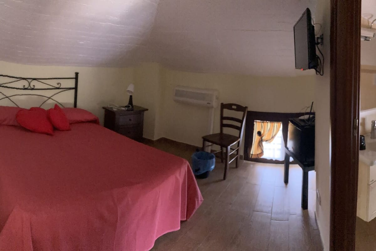 A bedroom with a bed, dresser, and a small table with a lamp.