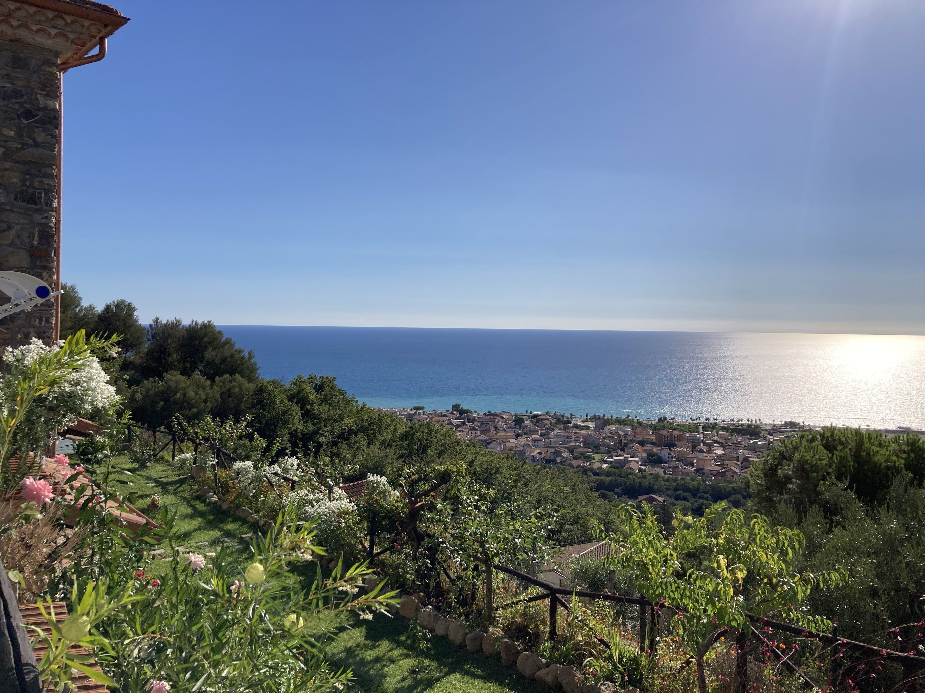 Une vue sur la côte, avec un bâtiment en pierre, une végétation luxuriante et un ciel dégagé.