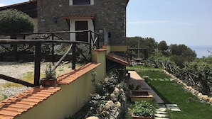 A stone building with a tiled roof, a small window, and a staircase leading to a balcony. - Relais da Clorinda (Ascea)
