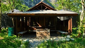 Une cabane rustique en bois, dotée d’un toit en pente, d’un espace salon abrité et d’un foyer.
