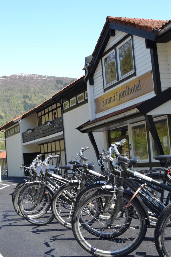 A building with a sign reading "Strand Fjordhotel" and several bicycles parked in front.