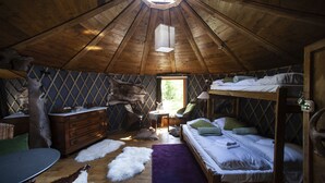 Une chambre mansardée chaleureuse avec un plafond en bois incliné, un lit superposé, une commode, une petite table et une chaise.
