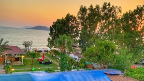 Un resort con posti a sedere all'aperto, una piscina e vista sul mare al tramonto.