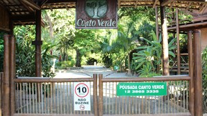 A wooden gate with a sign that reads "Pousada Canto Verde" and a speed limit sign of 10 km/h. - Pousada Canto Verde (São Sebastião)