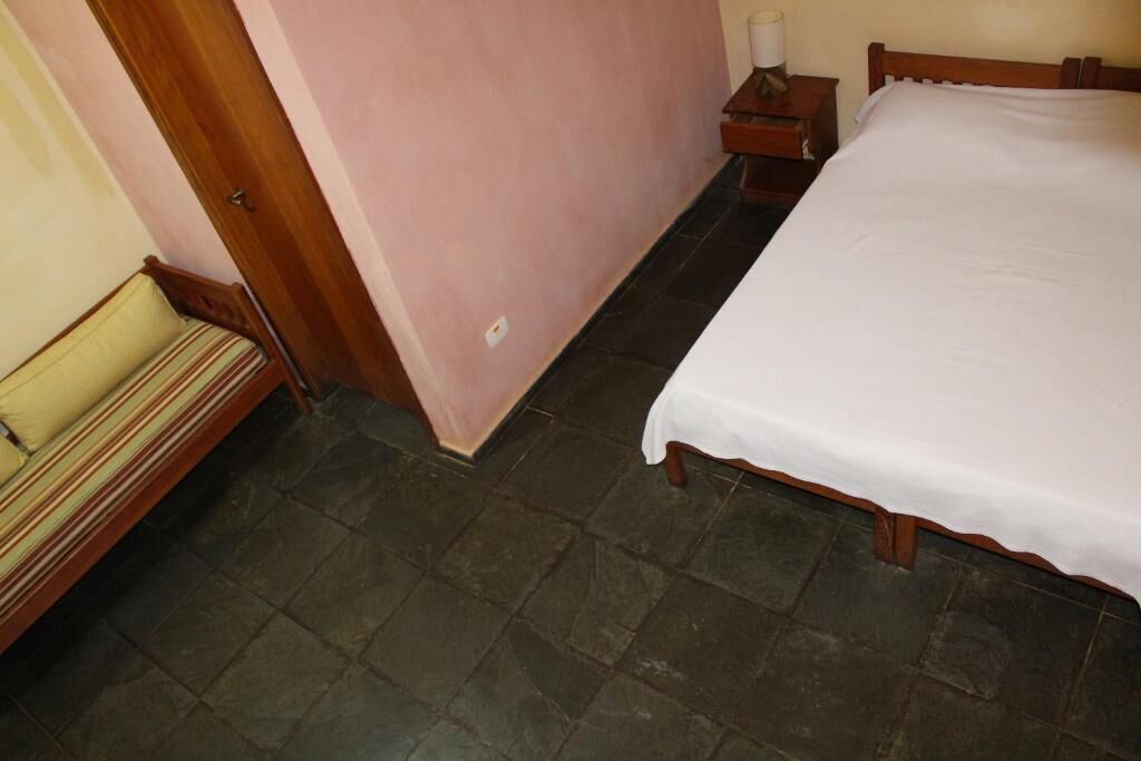 Quarto com uma cama, uma mesa de cabeceira, uma luminária e um banco.