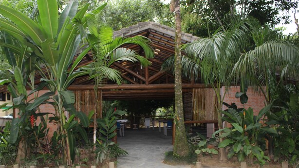 A rustic wooden structure with a thatched roof, surrounded by lush tropical vegetation. - Pousada Canto Verde (São Sebastião)
