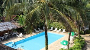 A swimming pool surrounded by lounge chairs and palm trees. - Pousada Canto Verde (São Sebastião)