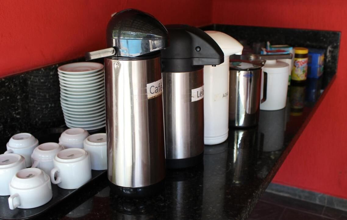 A coffee station with several coffee makers and disposable cups.