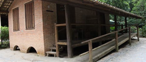 Un edificio rústico de ladrillo con un porche de madera y escalones que conducen a un espacio cubierto.