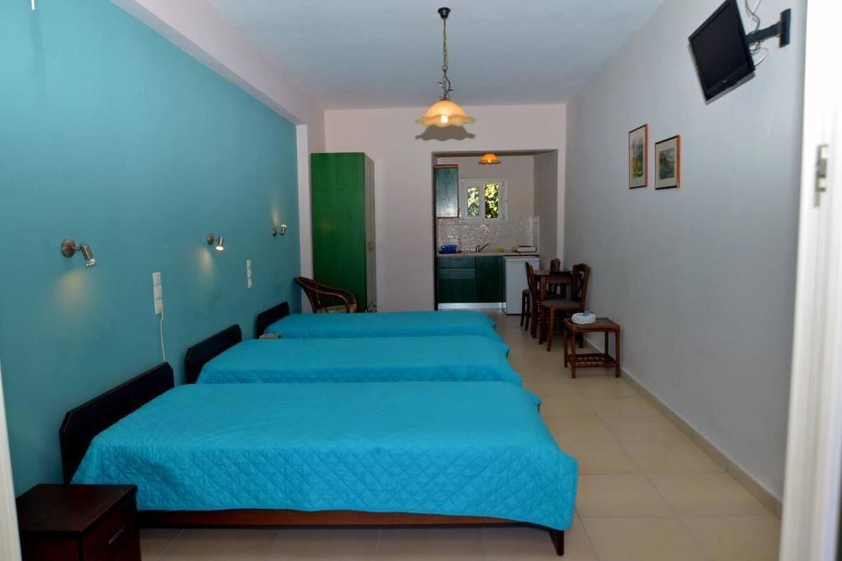 A room with two beds, a kitchenette, and a dining area.
