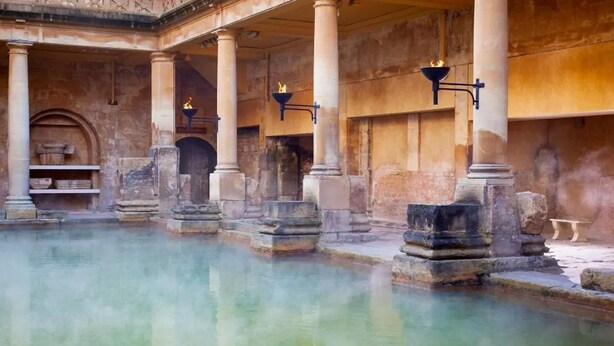 Ein historisches Gebäude mit einem zentralen Pool, steinernen Säulen und rundbogigen Durchgängen.