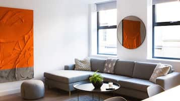 A modern living room with a grey sofa, round coffee table, and a large orange abstract painting on the wall.