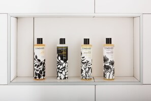 Four bottles of Cowshed bath and shower gel in a white display case. - Hiding Space - Westgate Apartments (Bath)