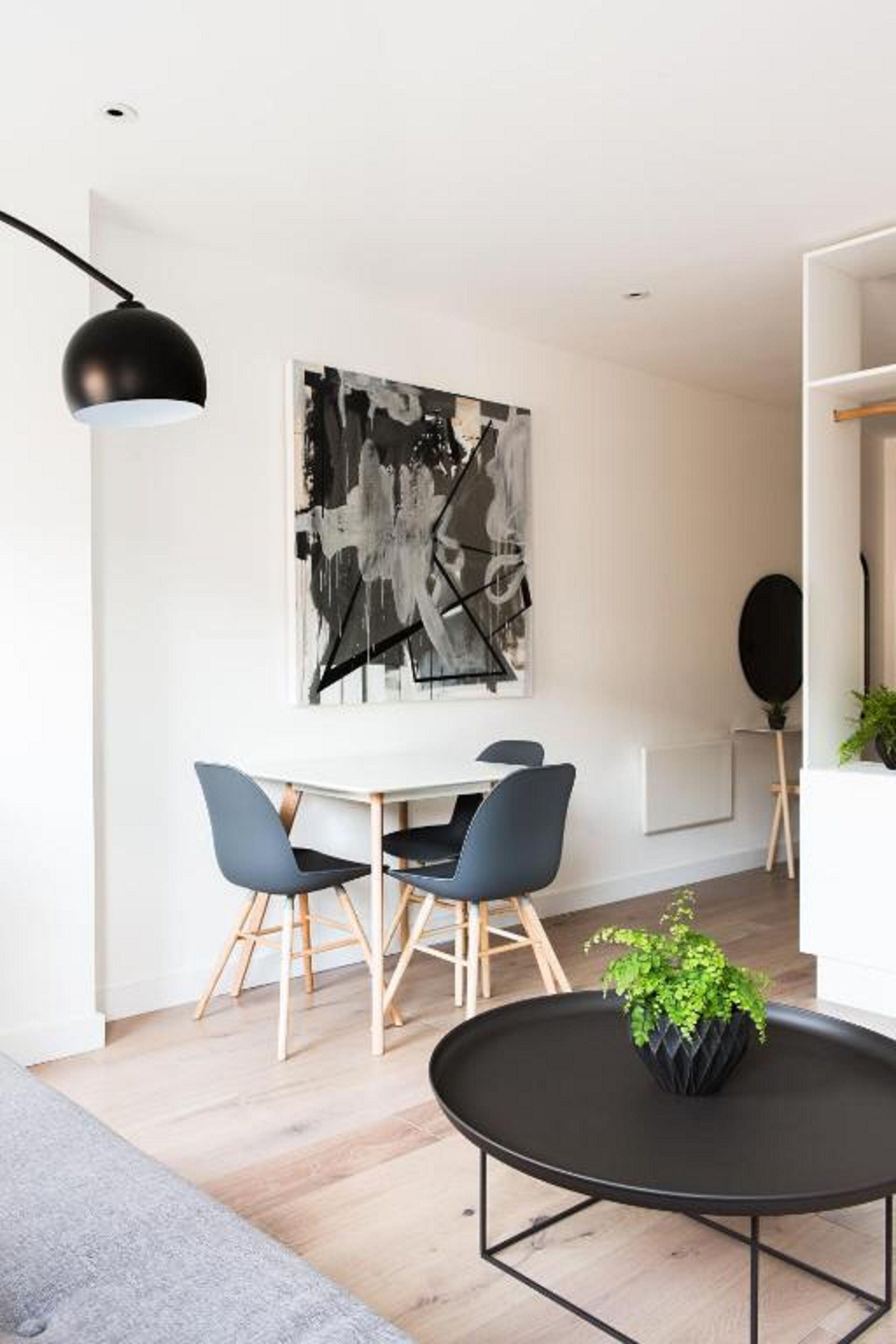 Een moderne eethoek met een witte tafel, twee blauwe stoelen en een zwarte vloerlamp.