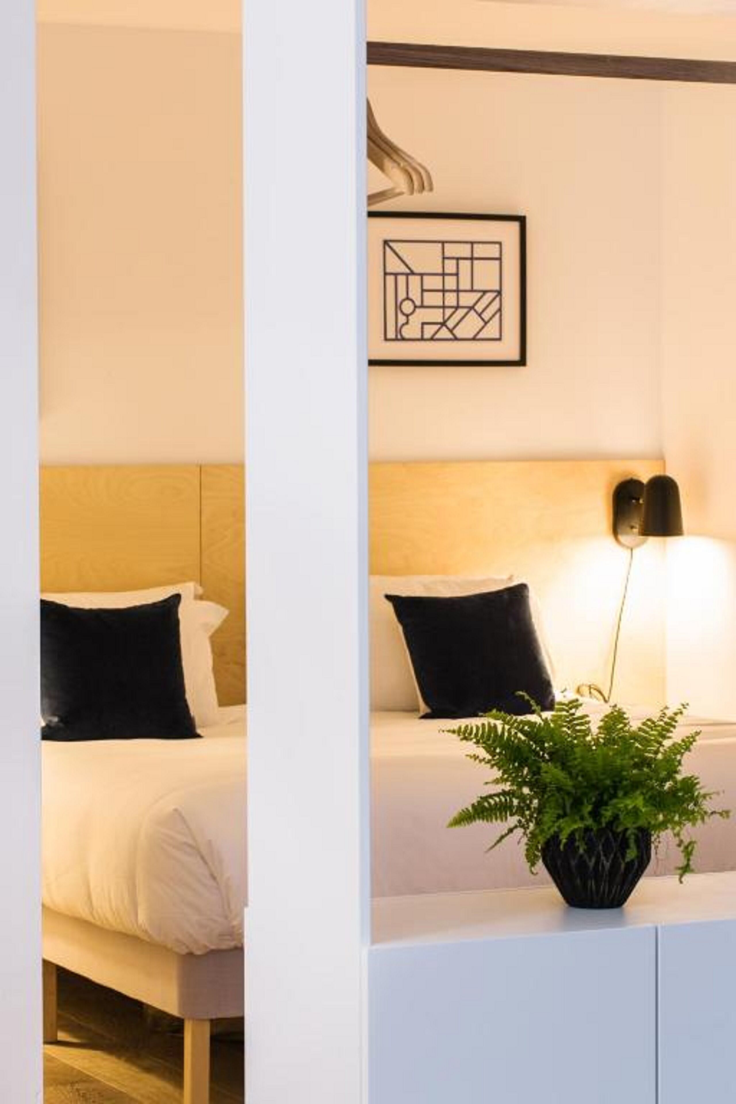 Et hotelværelse med en seng, et natbord med lampe og et billede i ramme på væggen.